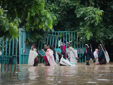 Orang-orang melintasi jalan yang tergenang air setelah hujan monsun di Gurgaon di pinggiran New Delhi (19/8/2020). Hujan lebat melanda New Delhi pada 19 Agustus, membanjiri jalan dan menumpuk kesengsaraan bagi penumpang di ibu kota India yang kacau balau. (AFP/Xavier Galiana)