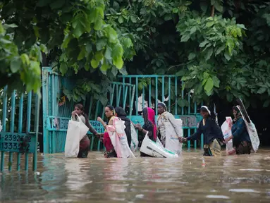 Orang-orang melintasi jalan yang tergenang air setelah hujan monsun di Gurgaon di pinggiran New Delhi (19/8/2020). Hujan lebat melanda New Delhi pada 19 Agustus, membanjiri jalan dan menumpuk kesengsaraan bagi penumpang di ibu kota India yang kacau balau. (AFP/Xavier Galiana)