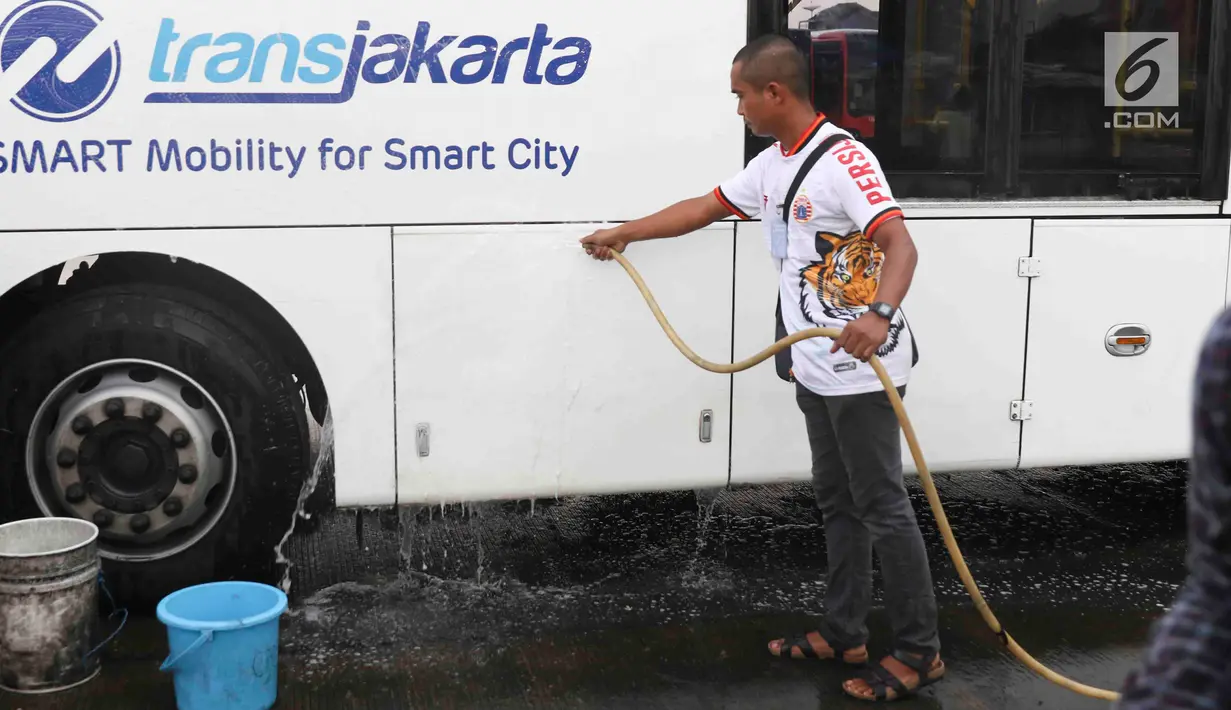 Suporter Persija Jakarta mencuci bus transjakarta di kantor PT Transjakarta, Jakarta, Kamis (13/12). Hal tersebut dilakukan bentuk tanggung jawab atas aksi vandalisme oknum suporter saat Persija meraih Juara Liga 1 2018. (Liputan6.com/Immanuel Antonius)