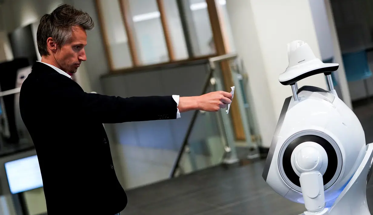 Seorang karyawan perusahaan Belgia, ZoraBots, memperlihatkan kode QR selama pengujian robot yang disebut CRUZR di Antwerp University Hospital (UZA) pada 29 Mei 2020. Robot ini dapat mendeteksi demam serta mengetahui pengunjung rumah sakit  yang memakai Masker atau tidak. (Kenzo TRIBOUILLARD/AFP)