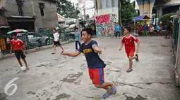 Ekspresi salah satu remaja saat bermain sepak bola di kolong rel kereta kawasan Juanda, Jakarta, Jumat (27/5). Tidak tersedianya ruang terbuka menyebabkan lahan tersebut dijadikan tempat bersosialisasi bagi warga. (Liputan6.com/Immanuel Antonius)
