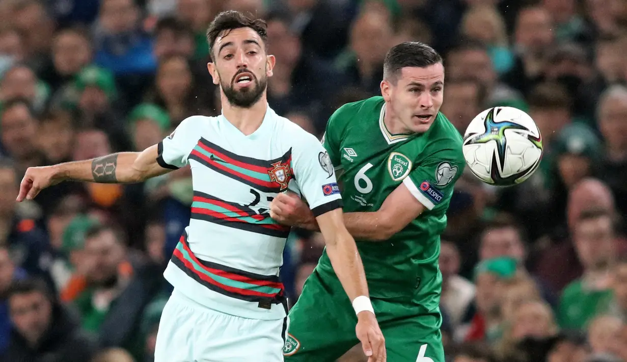 Gelandang Portugal Bruno Fernandes (kiri) berebut bola dengan gelandang Republik Irlandia Josh Cullen pada laga Grup A Kualifikasi Piala Dunia 2022 Zona Eropa di Stadion Aviva, Jumat (12/11/2021) dinihari WIB. Diwarnai kartu merah Pepe, Portugal ditahan imbang 0-0 oleh Irlandia. (Paul Faith / AFP)
