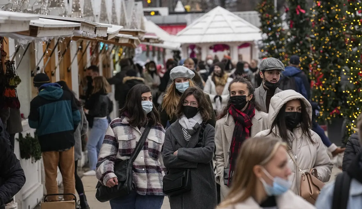 Pembeli mengenakan masker berjalan di sepanjang pasar Natal di taman Tuilerie di Paris, 20 Desember 2021. Negara-negara di Eropa mempertimbangkan pembatasan yang lebih ketat guna membendung gelombang baru infeksi COVID-19 yang didorong oleh varian omicron yang sangat menular. (AP Photo/Michel Euler)