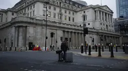 Seorang pria berjalan membawa koper melewati Bank of England pada pagi pertama penerapan lockdown nasional ketiga di Kota London, Inggris, 5 Januari 2021. Inggris menerapkan lockdown nasional ketiga untuk membendung lonjakan infeksi COVID-19 yang mengancam rumah sakit. (AP Photo/Matt Dunham)