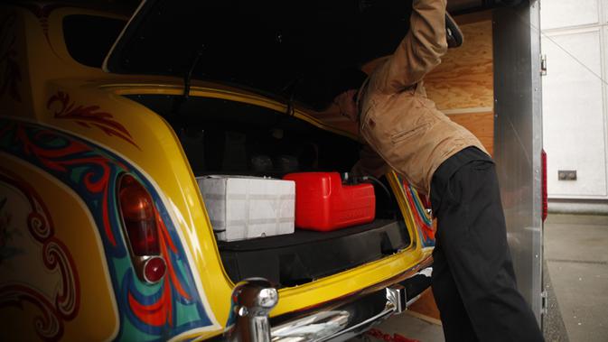 Seorang pria melihat bagasi Rolls-Royce limusin touring Phantom V milik John Lennon Museum Royal BC di Victoria, British Columbia (27/1/2020). Mobil ini pernah membawa John Lennon dan Yoko Ono ke New York City pada tahun 1970. (Chad Hipolito/The Canadian Press via AP)