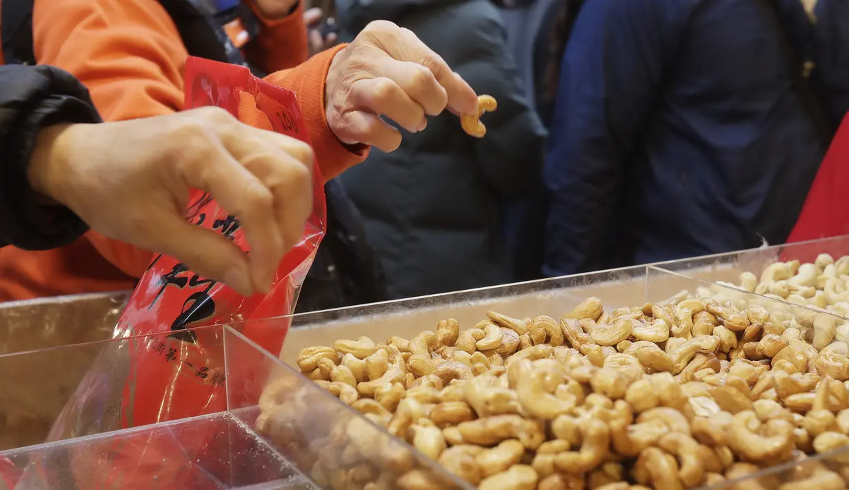 Pengunjung mencicipi jajanan kering di pasar Jalan Dihua di Taipei, Taiwan, Jumat, 20 Januari 2023. Pembeli Taiwan mulai berburu makanan lezat, jajanan kering, dan barang murah lainnya di pasar menjelang perayaan Tahun Baru Imlek yang menurut kalender lunar akan berlangsung pada 22 Januari. (AP Photo/Chiang Ying-ying)