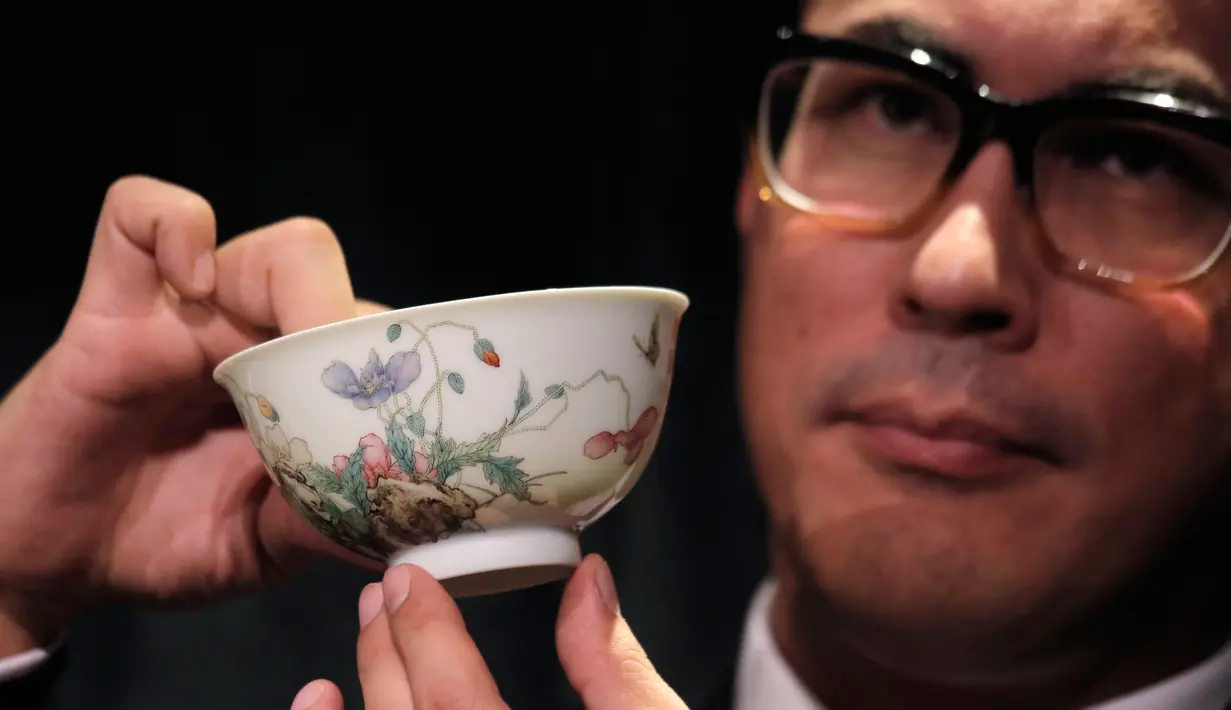 Pegawai rumah lelang Sotheby's memeng mangkuk falangcai dari Dinasti Qing selama pratinjau media di Hong Kong, Kamis (30/8). Dinasti Qing berkuasa di China pada tahun 1644  hingga 1911. (AP Photo/Kin Cheung)