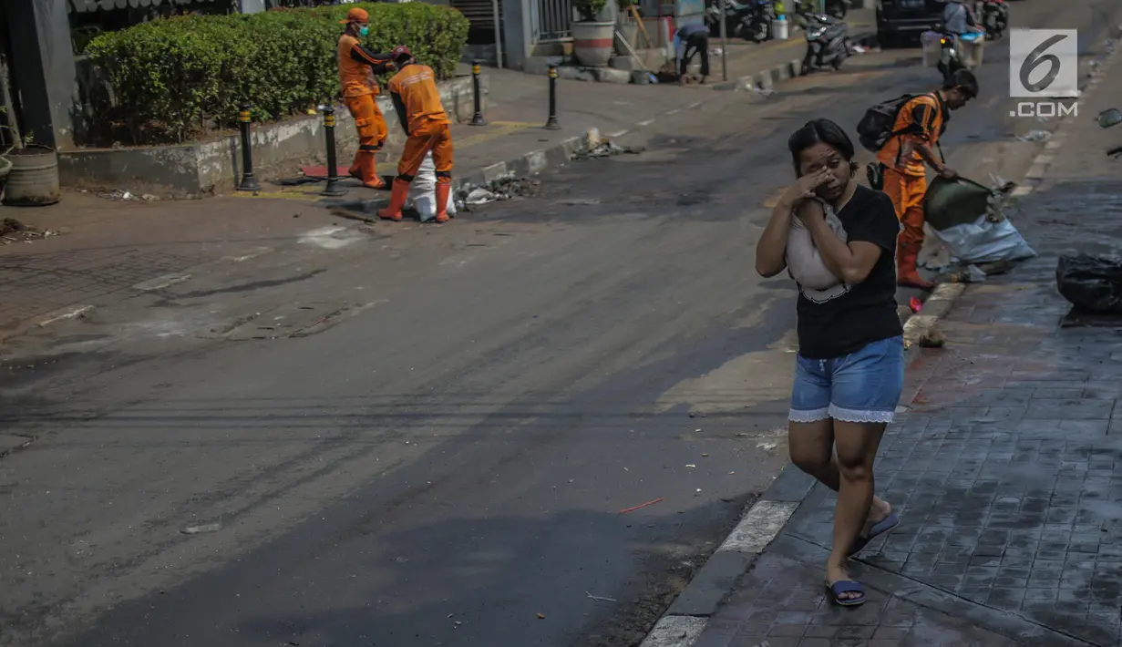 Warga menutupi matanya untuk menghindari sisa gas air mata pasca bentrok massa dengan aparat di Palmerah, Jakarta, Kamis (26/9/2019). Banyak masyarakat yang melintas dan warga sekitar perih pada mata hingga bersin akibat sisa gas air mata pasca bentrokan kemarin. (Liputan6.com/Faizal Fanani)