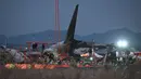 <p>Petugas pemadam kebakaran dan penyelamat masih terus bekerja di dekat lokasi pesawat Jeju Air berjenis Boeing 737-800 yang jatuh dan terbakar di Bandara Internasional Muan, Provinsi Jeolla Selatan, sekitar 288 kilometer sebelah barat daya Seoul, Korea Selatan pada Minggu 29 Desember 2024. (JUNG YEON-JE/AFP)</p>