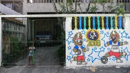 Seorang gadis berdiri di belakang gerbang pada sebuah mural Piala Dunia 2018 di dinding jalanan Camboata, Rio de Janeiro, Brasil, Kamis (31/6). (Fabio TEIXEIRA/AFP)