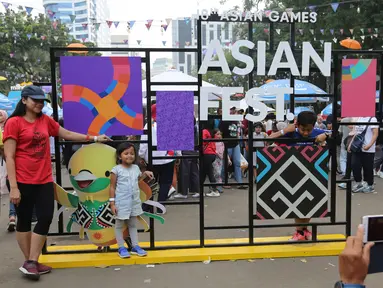 Ibu dan anak foto bersama di landmark Asian Festival 2018 di kawasan Gelora Bung Karno Senayan, Jakarta, Minggu (2/9). Jelang Closing Ceremony Asian Games 2018 calon penonton memadati komplek GBK. (Liputan6.com/Fery Pradolo)