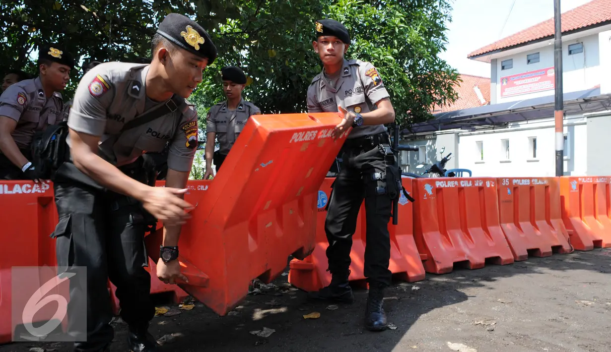 Polisi satuan Brimob mengangkat Water Barrier untuk barikade pengamanan menuju Dermaga Nusakambangan, Cilacap, Jawa Tengah, Rabu (27/7). Menjelang eksekusi Tahap 3 sejumlah persiapan dilakukan oleh Lapas Nusakambangan. (Liputan6.com/Helmi Afandi)