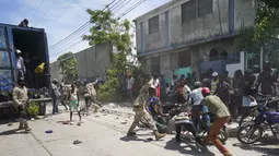 Polisi menghadapi warga yang untuk sementara menyalip sebuah truk yang penuh dengan pasokan bantuan, di Les Cayes, Haiti, Jumat (20/8/2021).  Bantuan swasta dan kiriman dari pemerintah AS dan lainnya tiba di semenanjung barat daya negara itu. dilanda. (AP Photo/Fernando Llano)