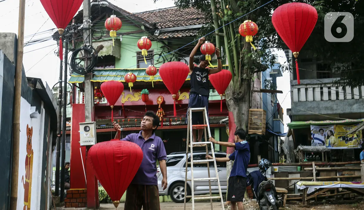 Warga menghias jalan dengan lampion di Kampung Limo, Depok, Jawa Barat, Rabu (26/1/2022). Kampung dengan sejumlah warga keturunan Tionghoa tersebut menyambut perayaan Tahun Baru Imlek 2022 dengan menghias gapura dan jalan dengan pernak-pernik Imlek. (Liputan6.com/Johan Tallo)