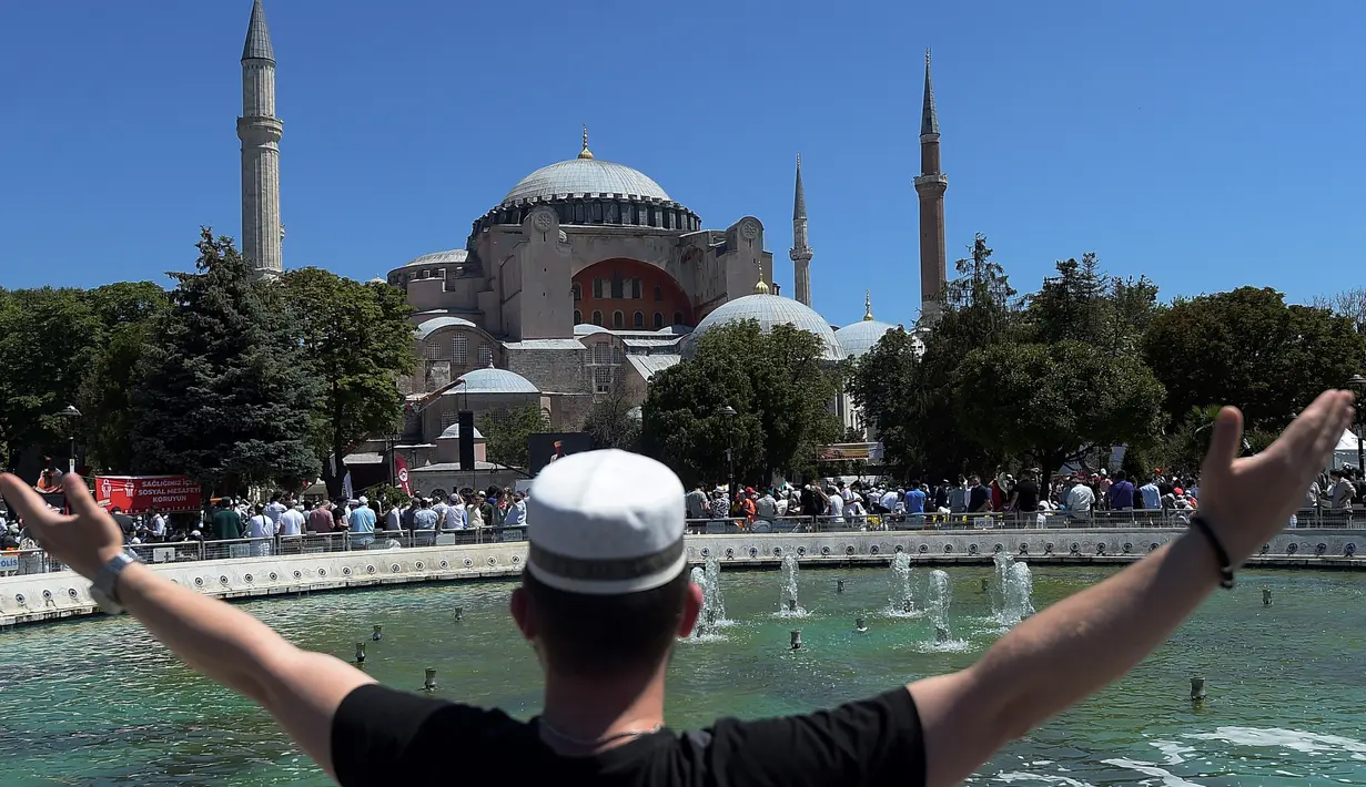 Seorang pemuda memberi isyarat saat menunggu di luar Hagia Sophia, Istanbul, Turki, Jumat (24/7/2020). Umat muslim melaksanakan salat Jumat pertama di Hagia Sophia dalam 86 tahun terakhir. (AP Photo/Yasin Akgul)