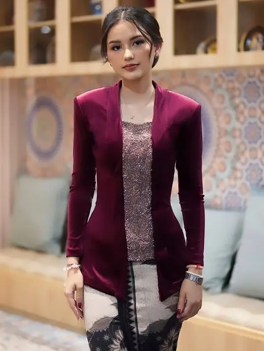 Sarah Menzel dibalut kebaya velvet polos berwarna merah wine yang cantik, di bagian tengahnya dibuat berkilauan, dan ia memadukannya dengan kain batik berwarna gelap sebagai rok. [Foto: Instagram/windysavosacouture]