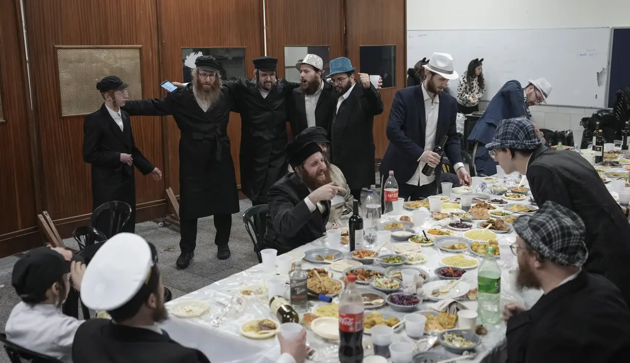 Pengungsi Ukraina Yahudi Ultra-Ortodoks yang melarikan diri dari perang merayakan festival Yahudi Purim di Yerusalem (18/3/2022). Hari libur Yahudi Purim memperingati keselamatan orang-orang Yahudi dari genosida di Persia kuno, seperti yang diceritakan dalam Kitab Ester. (AP Photo/Mahmoud Illean)