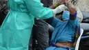 Seorang petugas kesehatan mengumpulkan sampel usap dari seorang wanita untuk menguji virus Covid-19 di daerah kumuh di Hyderabad (23/9/2020). Infeksi virus corona di India kembali melonjak pada Rabu (23/9) setelah sehari sebelumnya menyentuh angka terendah dalam hampir sebulan. (AFP/Noah Seelam)