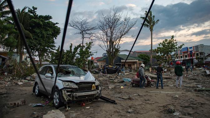 Orang-orang melihat kerusakan pantai yang terkena tsunami setelah gempa kuat disusul tsunami menghantam Kota Palu di Sulawesi Tengah, Sabtu (29/9). Dampak dari bencana tersebut melulunlantakkan bangunan dan ratusan jiwa meninggal dunia. (AFP/Bay ISMOYO)