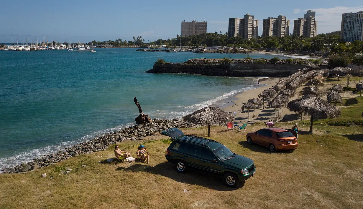 Pasangan Juan Peñalver dan Victoria Colina beristirahat di pantai Mansa setelah dibuka kembali di La Guaira, Venezuela, Jumat (23/10/2020). Pemberlakuan lockdown yang ketat akibat COVID-19 memaksa penutupan pantai di seluruh negeri pada Maret lalu dan dibuka kembali minggu ini. (AP/Matias Delacroix)