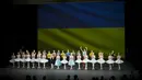 Penari Ukraina dari Balet Kota Kiev menerima tepuk tangan di depan bendera Ukraina yang diproyeksikan ke layar di akhir pertunjukan, di Theater de Chatelet, Paris (8/3/2022). Balet Kota Kiev menari dengan penuh semangat di Paris untuk pertunjukan terakhir dari tur Prancis. (AP Photo/Thibault Camus)