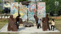 Pengunjung berfoto di depan Tembok Berlin di area RTH Kalijodo, Rabu (20/6). Banyaknya pilihan permainan buat anak-anak menjadikan RTH Kalijodo memiliki daya tersendiri untuk menghabiskan waktu libur bersama keluarga. (Lipiutan6.com/Helmi Fithriansyah)