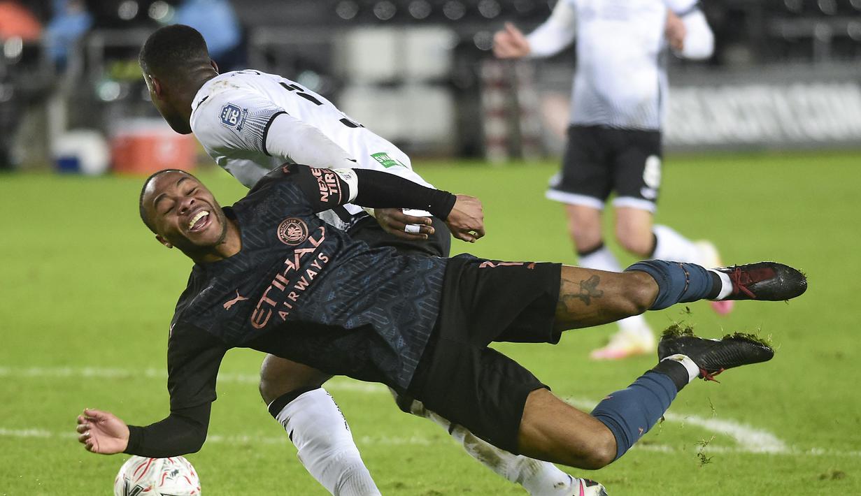 Gelandang Manchester City, Raheem Sterling (depan) terjatuh usai perebutan bola dengan bek Swansea City, Marc Guehi dalam laga babak kelima Piala FA 2020/21 di Liberty Stadium, Rabu (10/2/2021). Manchester City menang 3-1 atas Swansea City. (AFP/Rebecca Naden/Pool)