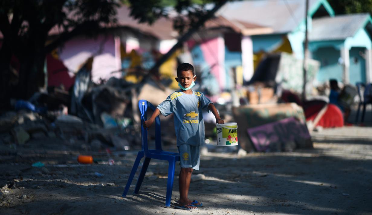 Seorang anak yang terkena dampak gempa meminta sumbangan pada pengguna jalan yang melintas di Donggala, Sulawesi Tengah, Jumat (5/10). Akibat terlambatnya pasokan bantuan, mereka terpaksa meminta sumbangan hingga turun ke jalan. (AFP PHOTO / Jewel SAMAD)
