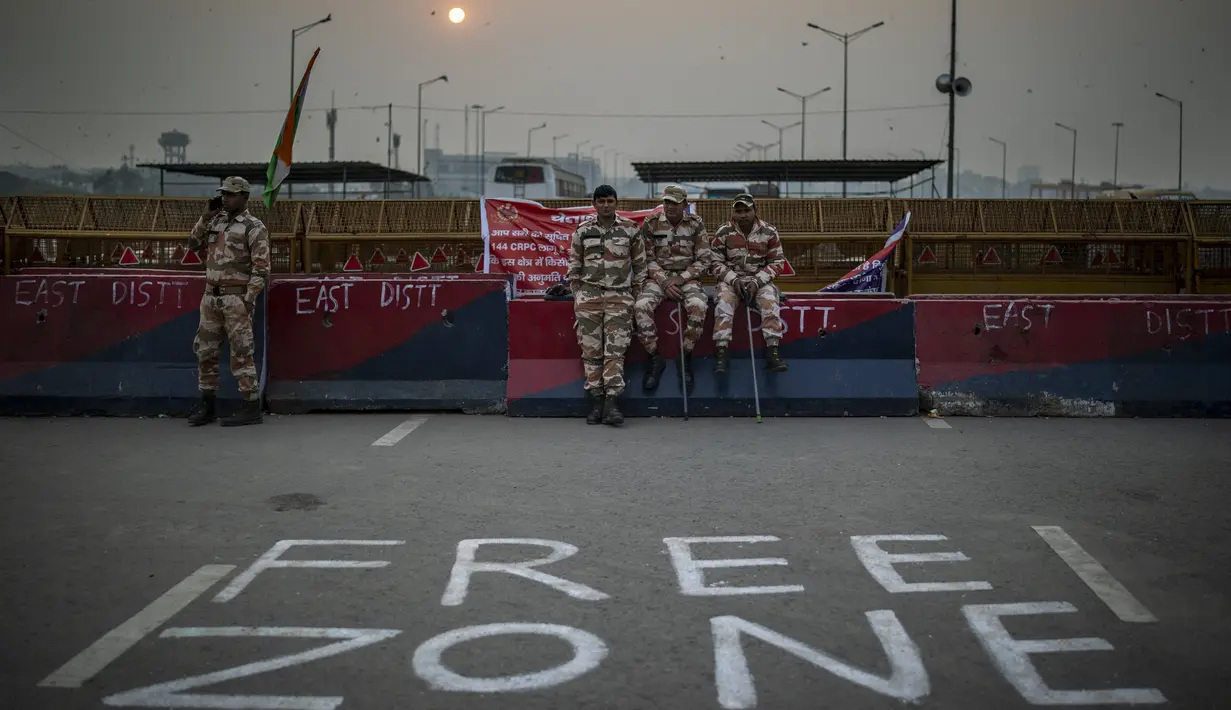 Tentara paramiliter India duduk di barikade di jalan tol utama yang diblokir oleh petani sebagai bagian dari protes di Ghazipur, pinggiran New Delhi, India, Kamis (9/12/2021). Para petani menuntut jaminan harga untuk tanaman utama dan penarikan kasus kriminal terhadap para pengunjuk rasa. (AP Photo/