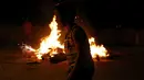 Seorang anak bermain didepan pinata Donald Trump yang telah dibakar saat perayaan tradisional, Pembakaran Iblis, Guatemala (7/12). Di tempat tersebut roh jahat itu direpresentasikan dalam bentuk tokoh politik kontemporer. (Reuters/Luis Echeverria)