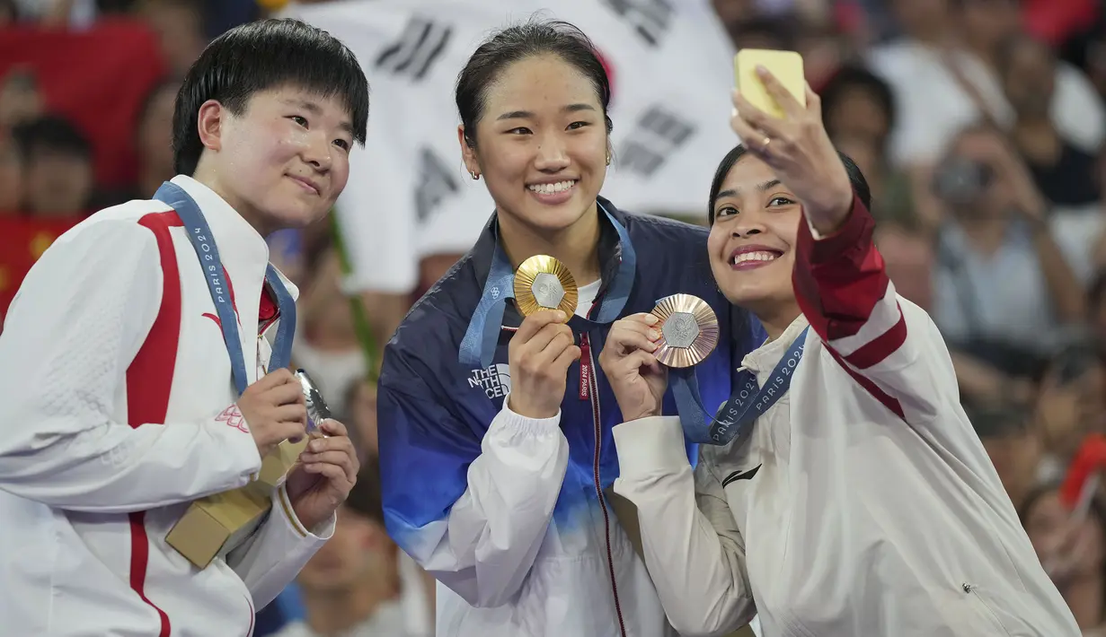 (Dari kanan) pebulu tangkis Indonesia peraih medali perunggu, Gregoria Mariska Tunjung, peraih medali emas An Se-young (Korea Selatan) dan peraih medali perak He Bing Jiao (Indonesia) berswafoto di atas podium saat upacara penyerahan medali nomor tunggal putri cabor bulu tangkis Olimpiade Paris 2024 di Porte de La Chapelle Arena, Paris, Senin (5/8/2024). (AP Photo/Kin Cheung)