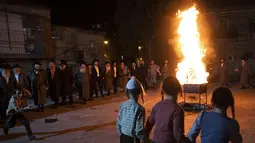 Yahudi Ultra-Ortodoks menari  di samping api unggun selama hari libur Yahudi perayaan Lag Ba'Omer di Bnei Brak, Israel, Kamis (29/4/2021). Liburan Lag Ba'Omer, menandai berakhirnya wabah yang dikatakan telah membinasakan orang Yahudi selama zaman Romawi. (AP Photo/Sebastian Scheiner)