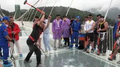 Seorang pria memukulkan palu untuk mencoba kekuatan kaca yang dipakai untuk jembatan di Provinsi Hunan, Cina, (25/6). Jembatan sepanjang 430 meter tersebut terbuat dari bahan kaca. (REUTERS / Jimmy Guan)
