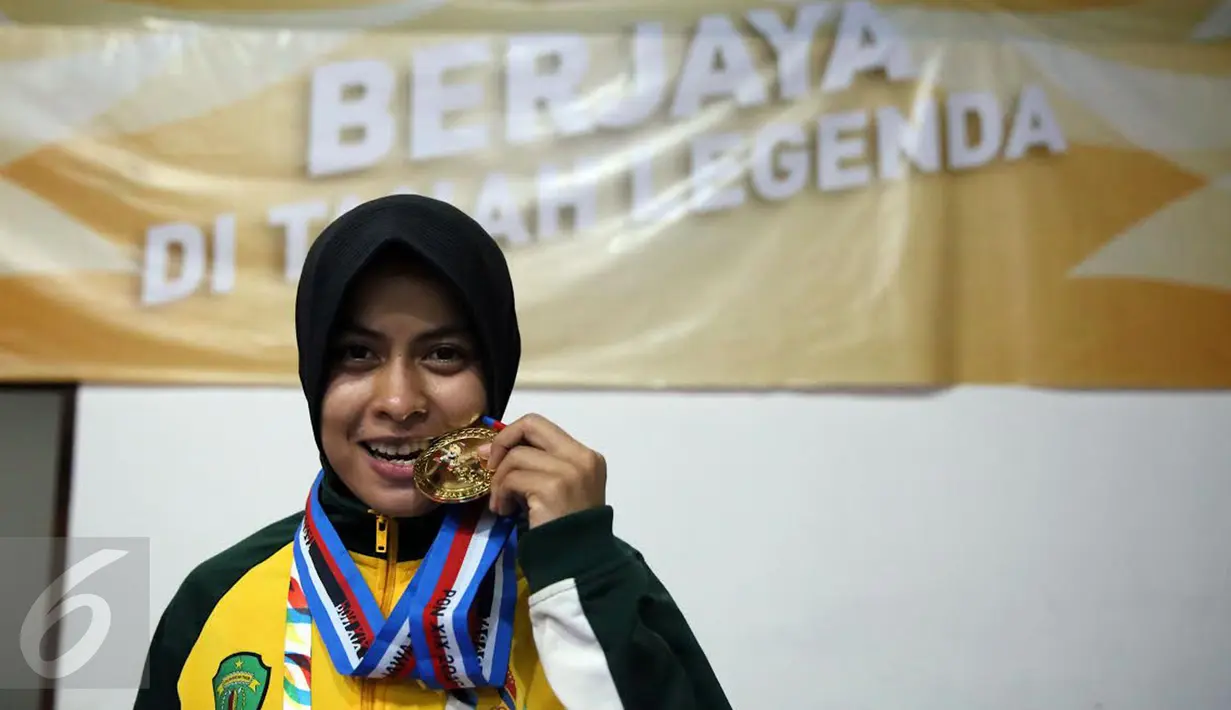 Pegulat putri Kaltim, Inadrah menggigit medali usai menang melawan pegulat Sumbar Mardiatul di final gaya bebas kelas 53 kg putri pada PON XIX di Arena Saparua Sport Park, Bandung, Sabtu (24/9). Inadrah berhasil raih emas (Liputan6.com/Helmi Fithriansyah)