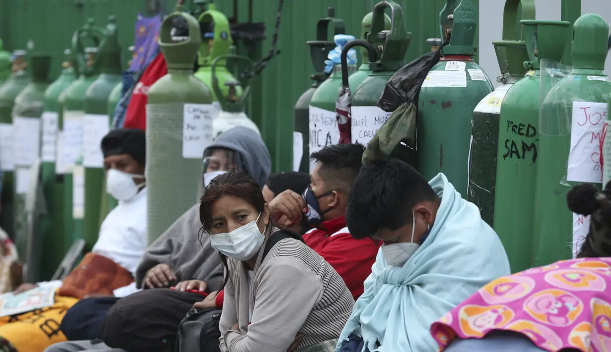 Orang-orang berkemah dengan tabung oksigen kosong mereka menunggu toko isi ulang dibuka di lingkungan San Juan de Lurigancho di Lima, Peru, Senin (22/2/2021). Kekurangan oksigen medis untuk merawat pasien COVID-19 terus menjadi norma nasional. (AP Photo/Martin Mejia)