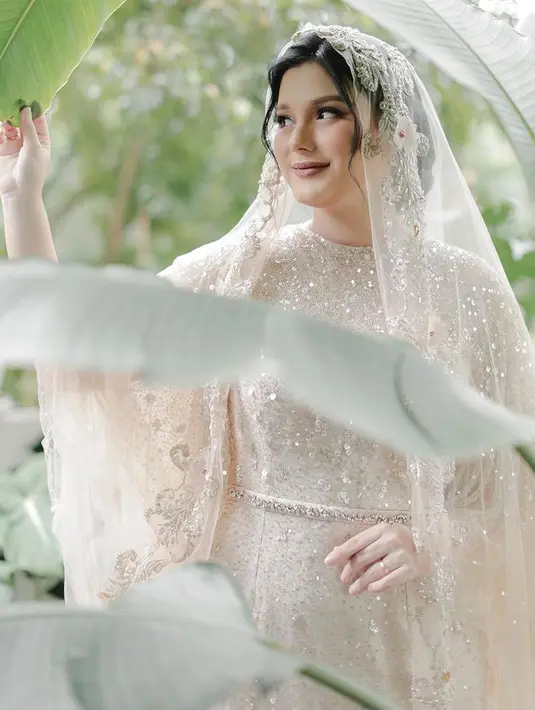 Dress warna nude ivory yang dikenakan Yasmine Ow ini memiliki detail lengan menjuntai.  @jnbphotographyofficial.