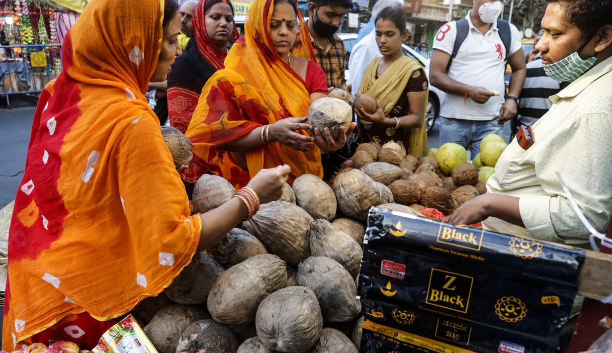 Dua wanita membeli kelapa di pinggir jalan menjelang festival Hindu Chhath, di Kolkata, India (9/11/2021). Selama Chhath, festival Hindu kuno yang populer di kalangan kelas pekerja, ritual dilakukan untuk berterima kasih kepada Dewa Matahari atas menopang kehidupan di bumi. (AP Photo/Bikas Das)