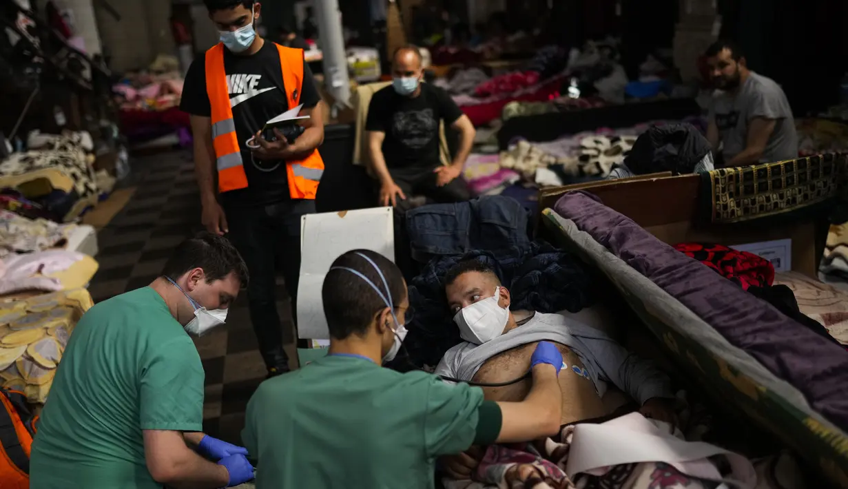 Petugas kesehatan Palang Merah memerika seorang pria yang mogok makan saat menempati gereja Saint-Jean-Baptiste-au-Beguinage di Brussel, Senin (7/6/2021). Puluhan migran tanpa surat resmi tersebut mogok makan untuk menarik perhatian otoritas Brussel atas penderitaan mereka. (AP Photo/Francisco Seco)