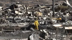 Petugas pemadam kebakaran berjalan di antara puing-puing yang terbakar di Erskine, South Lake, California, AS (24/6). Musibah yang disebabkan oleh kebakaran hutan ini telah menghanguskan sebuah perkampungan warga di California. (REUTERS/Noah Berger)
