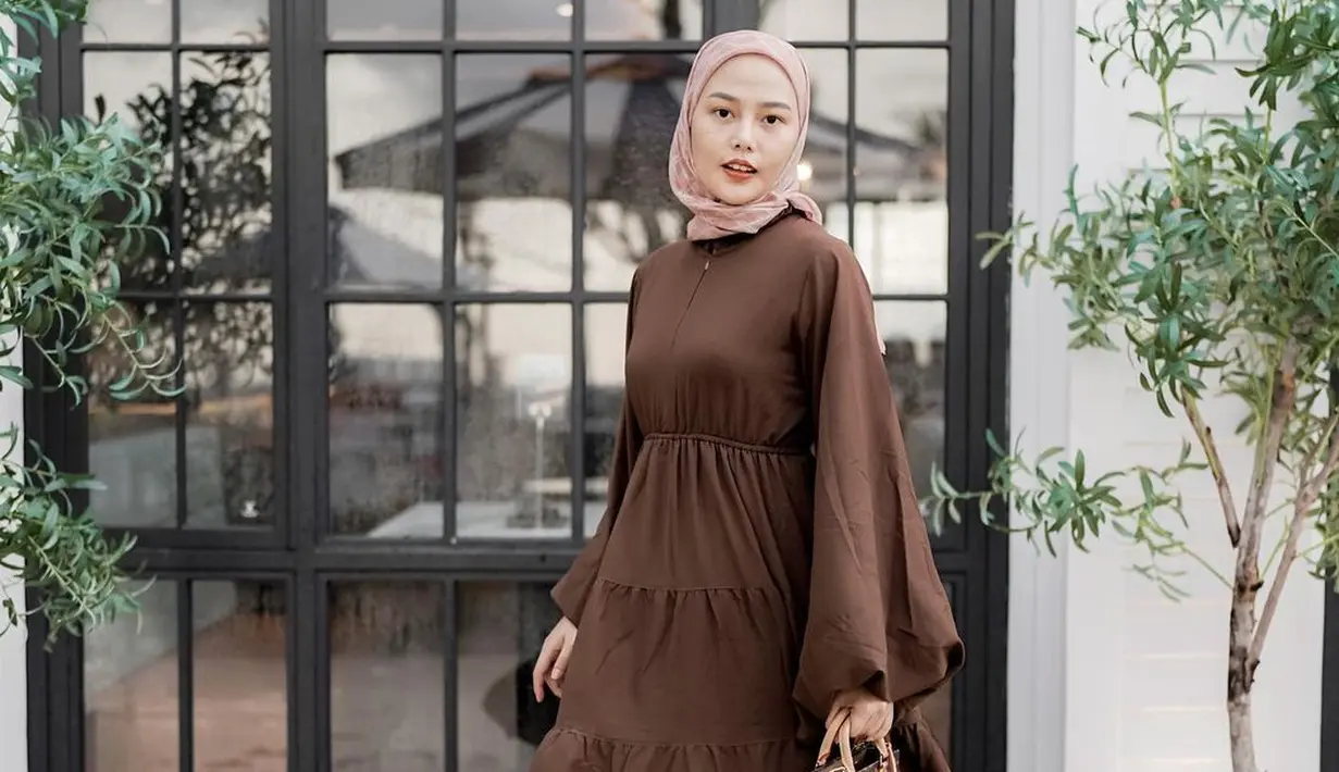 <p>Jadi cewek bumi, Dara kini mengenakan ruffle dress warna coklat yang dipadukan dengan hijab bermotif nuansa warna peach. (Instagram/ daraarafah).</p>