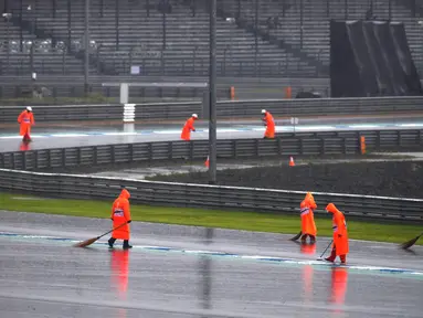 Pekerja menyapu air hujan ke luar lintasan saat sesi latihan dan kualifikasi kualifikasi MotoGP Thailand 2019 di Sirkuit Internasional Buriram, Sabtu (5/10/2019). Hujan deras mengakibatkan sesi latihan dan kualifikasi MotoGP Thailand 2019 ditunda. (Lillian SUWANRUMPHA/AFP)