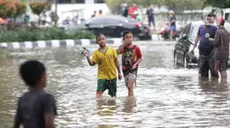 Anak anak bermain air di sebagian Jalan Bungur Besar Raya yang tergenang, Jakarta, Selasa (18/1/2022). Genangan air di sebagian Jalan Bungur Besar Raya dimanfaatkan anak-anak untuk bermain meski berbahaya. (Liputan6.com/Helmi Fithriansyah)