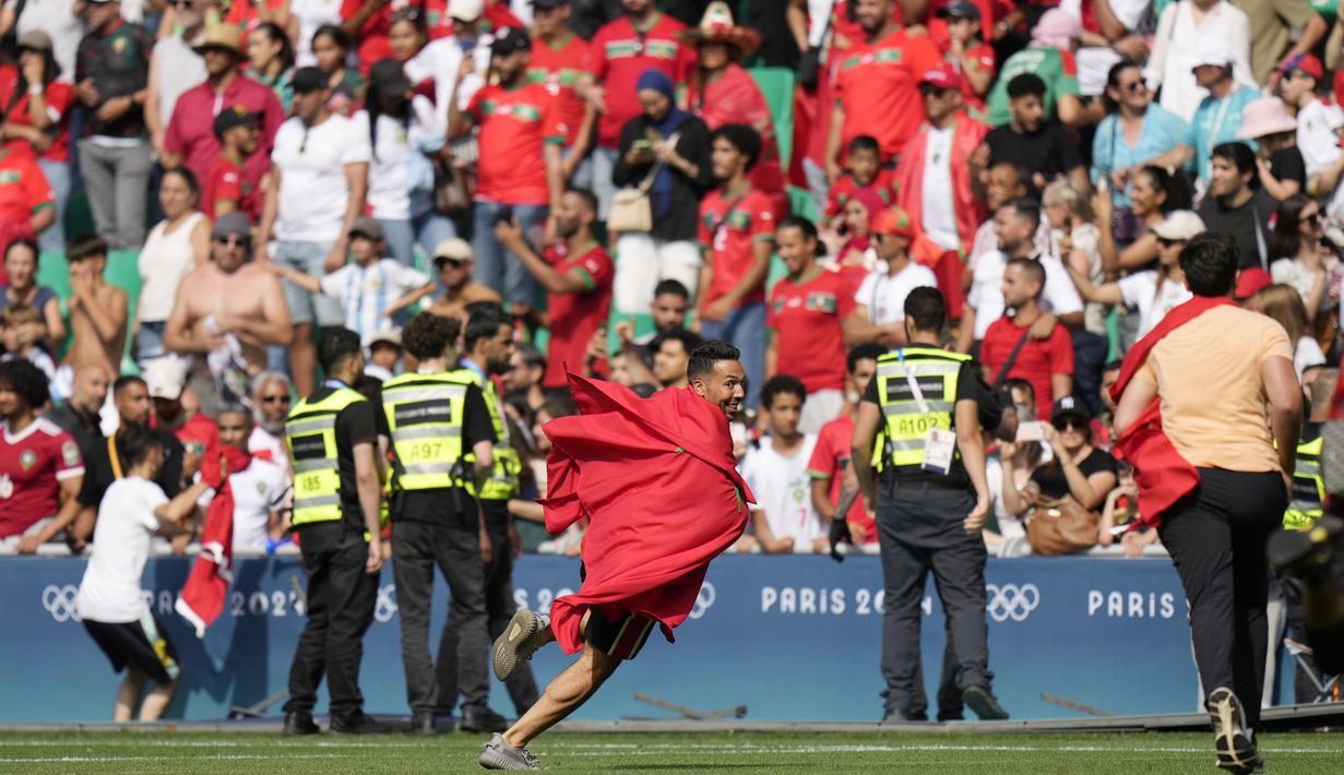 Suporter Maroko yang masuk ke dalam lapangan membuat pertandingan akhirnya terpaksa ditangguhkan selama 2 jam. Hingga laga berakhir Maroko mampu mempertahankan kemenangan dengan skor 2-1. (AP Photo/Silvia Izquierdo)