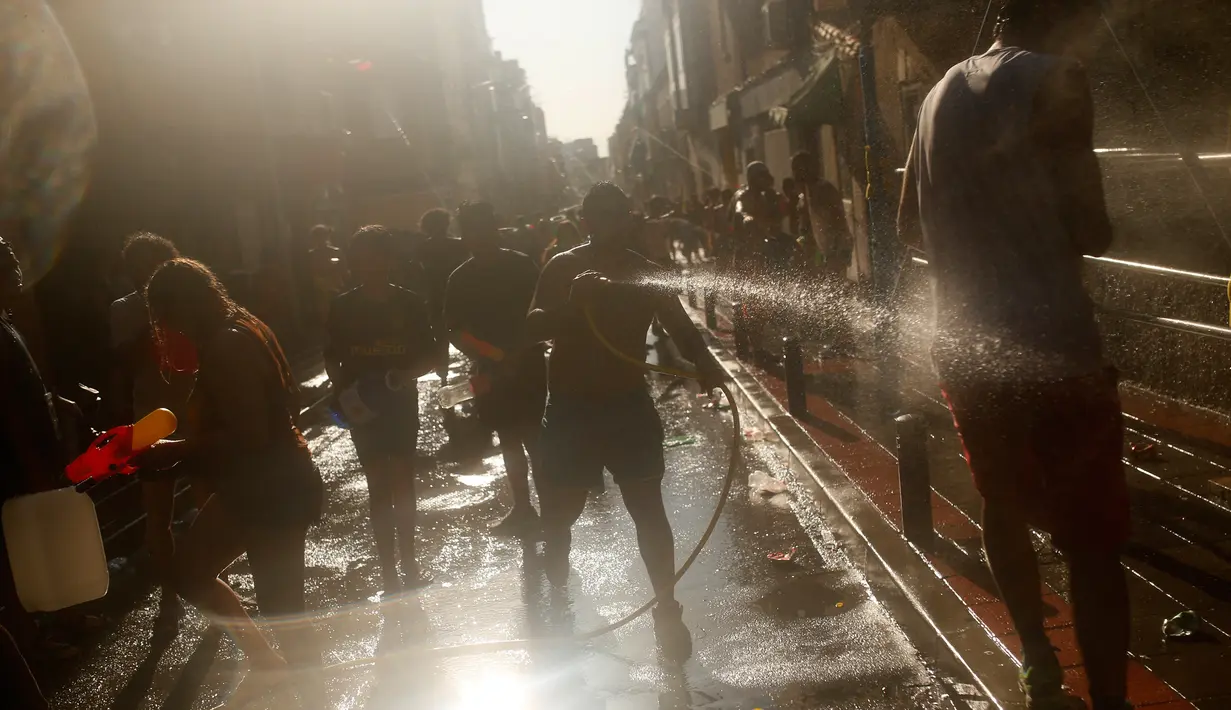 Seorang pria menyemprotkan air ke peserta lainnya saat mengikuti perang air tahunan di daerah Vallecas di Madrid, Spanyol (16/7). Asal-usul perang air ini dimulai sejak tahun 1981. (AP Photo / Francisco Seco)