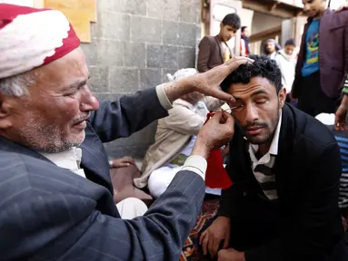 Seorang pria saat kelopak matanya dirias dengan kohl atau celak di  Masjid Agun di kota tua ibukota Sanaa, Yama, (19/5). Pemakaian kohl atau celak diyakini muslim Yaman mampu membersihkan dan melindungi mata dari penyakit. (AFP Photo/Mohammed Huvais)