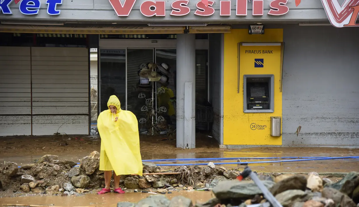Seorang wanita berdiri di air banjir menyusul badai petir yang hebat, di desa Agia Pelagia, di pulau Kreta, Yunani, Sabtu (15/10/2022). Dilaporkan setidaknya satu orang tewas dan lainnya hilang setelah banjir bandang yang parah. (AP Photo/Harry Nakos)
