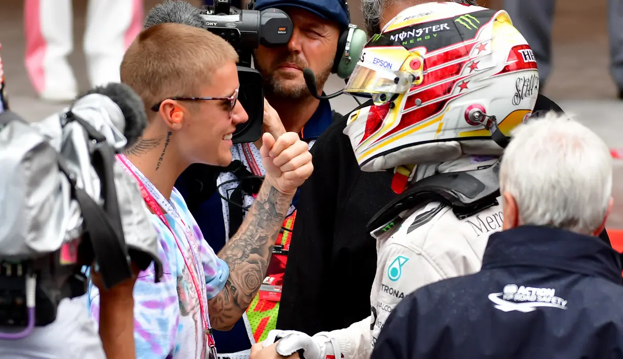 Penyanyi Justin Bieber memberikan selamat kepada pembalab Lewis Hamilton saat menjuarai Grand Prix di Monaco, (29/5). Ini merupakan kemenangan ke-44 sepanjang karier Hamilton. (AFP PHOTO/ANDREJ ISAKOVIC)