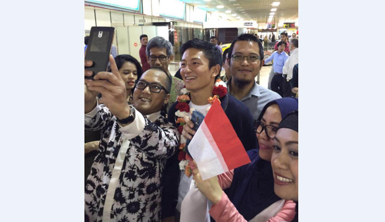 Pebalap Manor Racing asal Indonesia, Rio Haryanto, berfoto bersama staf KBRI Manama dan warga Indonesia yang menyambutnya di Bandar Udara Internasional Bahrain, Selasa (29/3/206). (Bola.com/Istimewa/Andri Hartanto)
