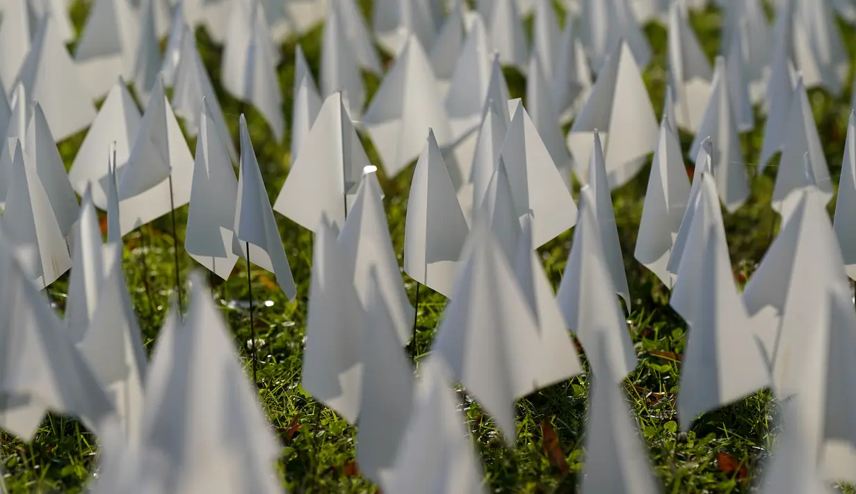 Matahari bersinar di atas bendera putih yang ditanam untuk mengenang warga Amerika yang meninggal karena COVID-19 di dekat Stadion RFK di Washington, Selasa (27/10/2020). Instalasi seni Suzanne Brennan Firstenberg itu disebut "In America, How Could This Happen.” (AP/Patrick Semansky)