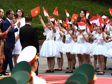 Presiden Jokowi dan Ibu Negara Iriana disambut puluhan anak berbaju balerina yang melambaikan bendera Vietnam dan Merah Putih, setibanya di Istana Kepresidenan, Hanoi, Vietnam, (11/9). (Nhac Nguyen/Pool photo via AP)